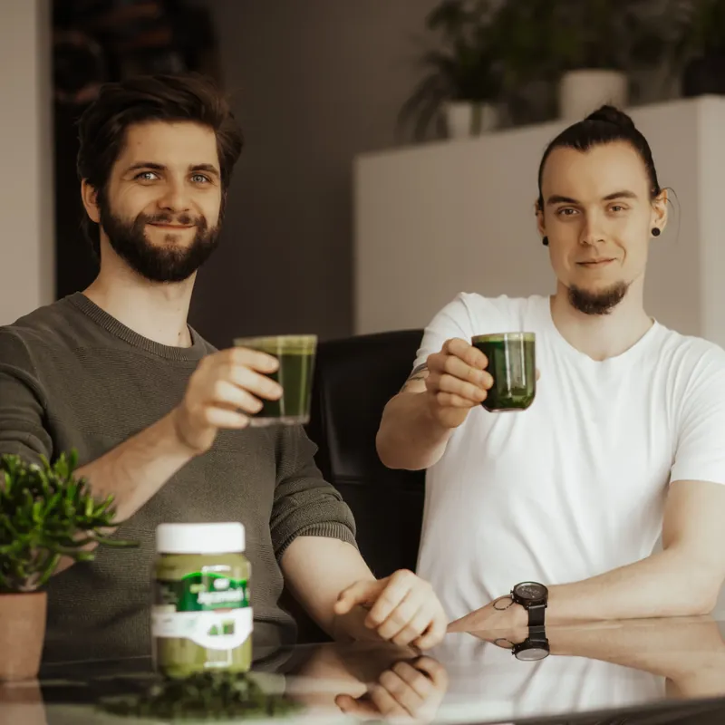 Założyciele Witalności wznoszą toast zielonymi napojami przy stole